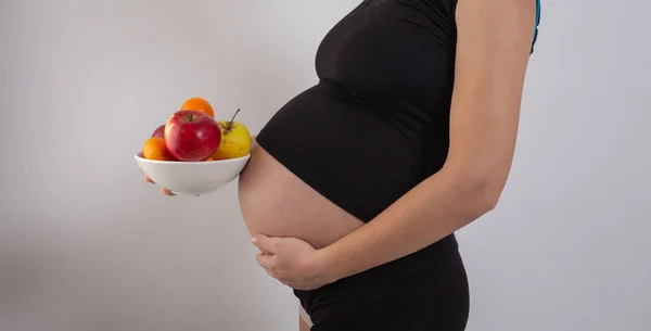 Pregnancy and healthy organic nutrition. Pregnant woman holds fresh vitamin fruits, free space. Place for text. Concept of expectation and health. — Stock Photo, Image