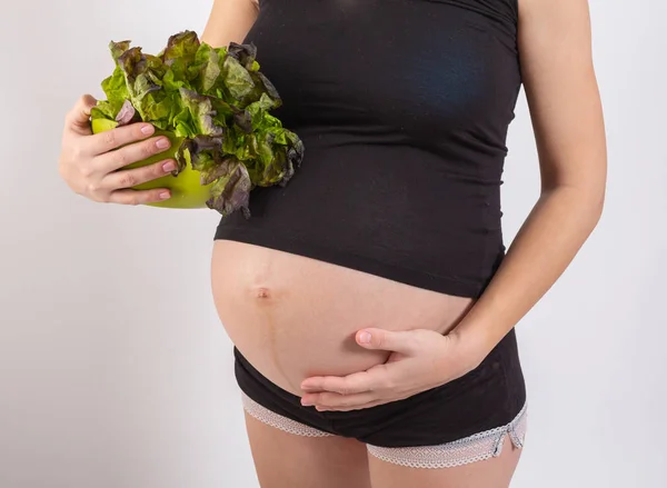Mujer embarazada sosteniendo ensalada fresca en el estudio — Foto de Stock