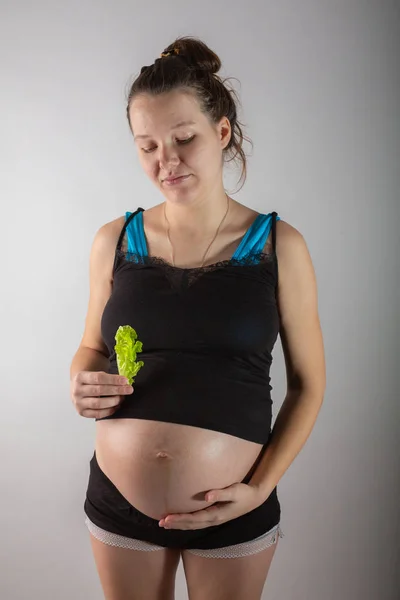 Těhotná žena drží čerstvý salát ve studiu — Stock fotografie