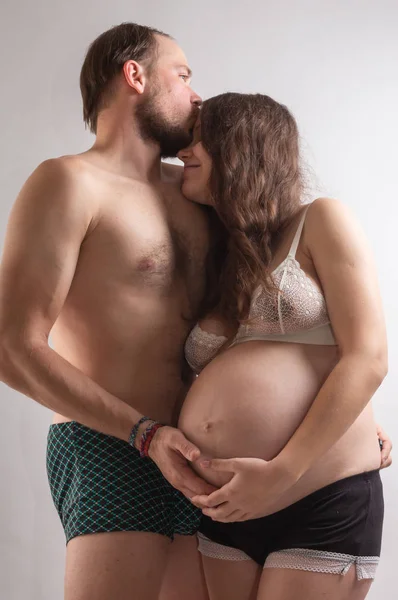 Mulher grávida bonita e seu belo marido estão se beijando enquanto passam tempo juntos na cama . — Fotografia de Stock