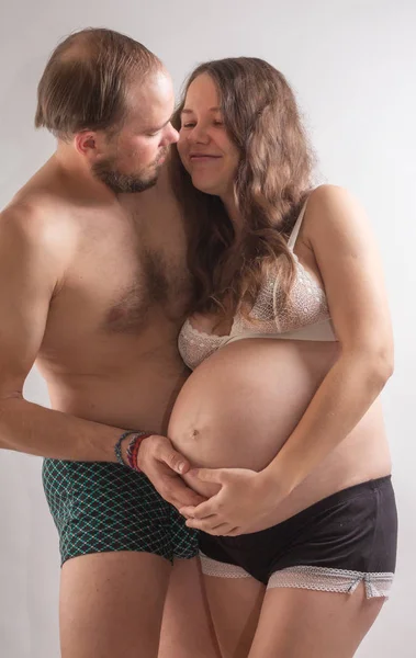 Mulher grávida bonita e seu belo marido estão se beijando enquanto passam tempo juntos na cama . — Fotografia de Stock