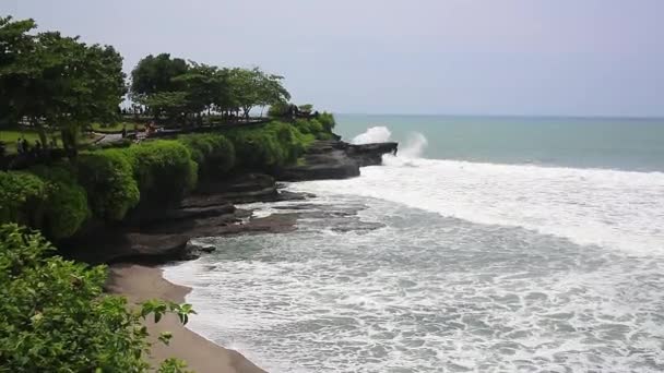 Vista estática aérea da superfície do oceano noturno, ondas calmas rolando na costa rochosa. Incríveis falésias altas acima do oceano e do templo de Uluwatu no topo. Bali, Indonésia — Vídeo de Stock