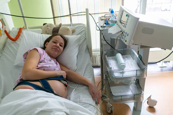 La femme enceinte ressent une forte contraction dans une salle d'accouchement de l'hôpital. Concept photo de grossesse, femme enceinte, nouveau-né et bébé . — Photo