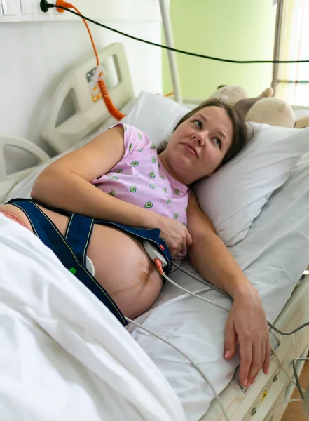 La femme enceinte ressent une forte contraction dans une salle d'accouchement de l'hôpital. Concept photo de grossesse, femme enceinte, nouveau-né et bébé . — Photo