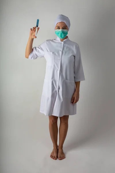 Девушка в медицинском пальто держит большой шприц с голубой жидкостью - коронавирусную вакцину — стоковое фото