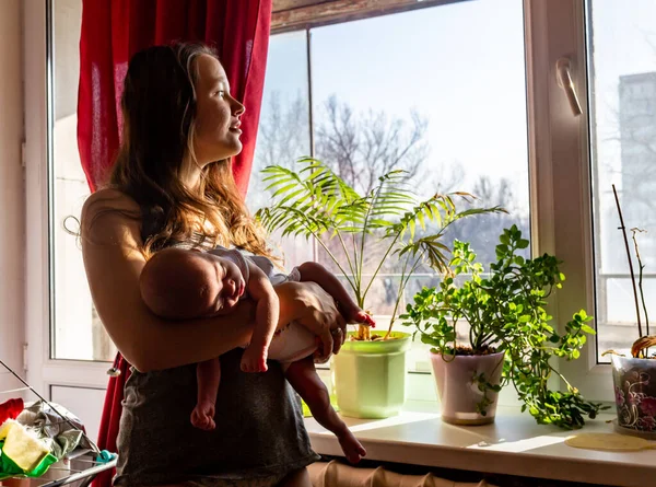 Mother and baby near the sunny window with home flowers — Stock Photo, Image