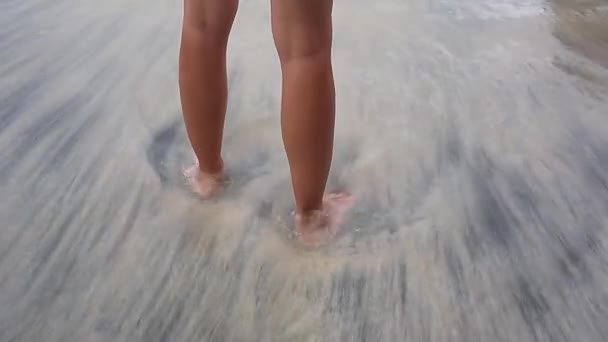 Pies de un joven caminando hacia el mar al atardecer . — Vídeo de stock