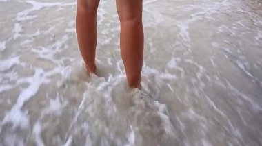 Gün batımında denize doğru yürüyen genç bir adamın ayakları..