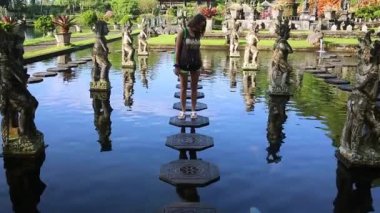 Endonezya 'nın Bali Adası' ndaki eski kraliyet sarayı Tirta Gangga su sarayını ziyaret eden genç bir turistin yavaş çekimleri.