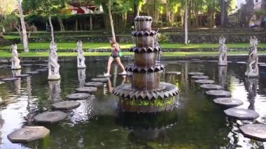 Endonezya 'nın Bali Adası' ndaki eski kraliyet sarayı Tirta Gangga su sarayını ziyaret eden genç bir turistin yavaş çekimleri.