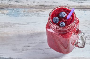 Ahşap beyaz bir masa üzerinde cam bir kavanozda çilek ile Meyve pembe yüzlü. Kopyalama alanı