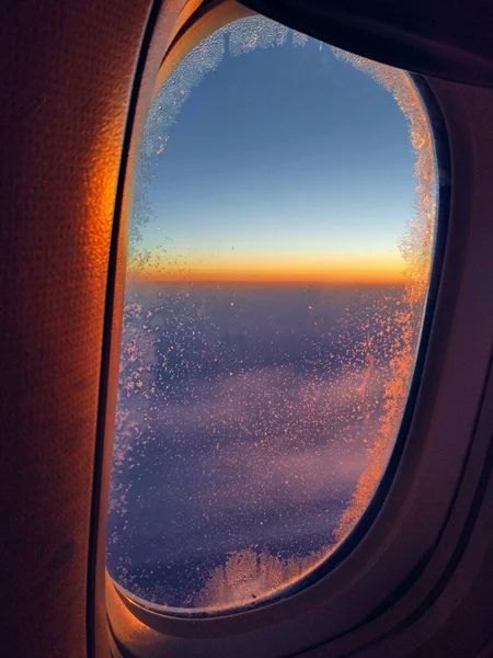 Zicht vanuit vliegtuigraam bij oranje en paarse zonsondergang. Gouden uur. Reizen en ontspannen concept — Stockfoto