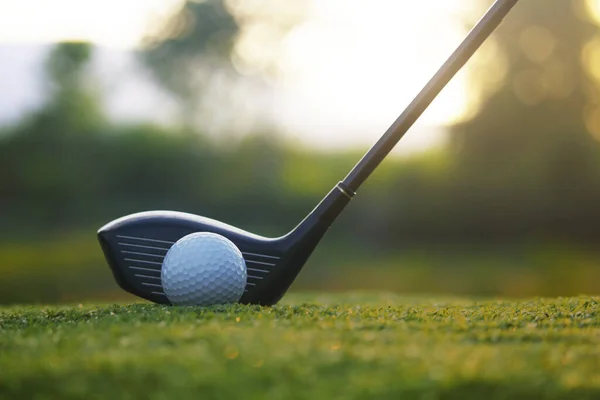 Golf clubs and golf balls on a green lawn in a beautiful golf course with morning sunshine.Ready for golf in the first short.Sports that people around the world play during the holidays for health.