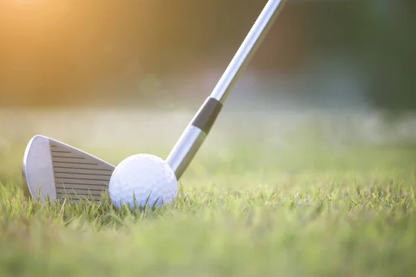 Golf clubs and golf balls on a green lawn in a beautiful golf course with morning sunshine.Ready for golf in the first short.Sports that people around the world play during the holidays for health.