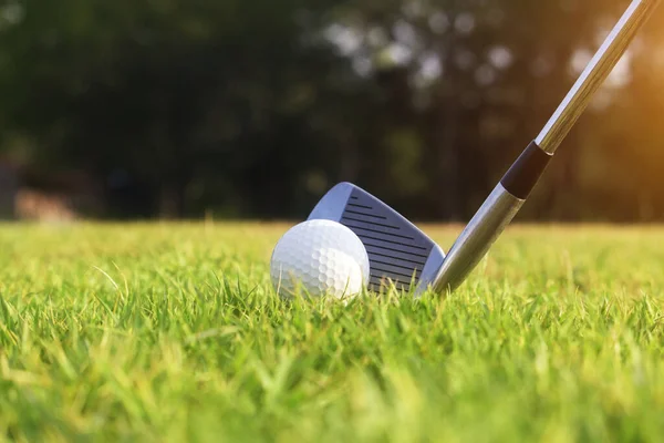 Golf clubs and golf balls on a green lawn in a beautiful golf course with morning sunshine.Ready for golf in the first short.Sports that people around the world play during the holidays for health.