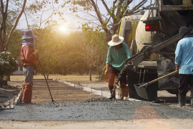 İşçiler çimento karıştırıcı kamyonuyla beton döküyorlar. Yol inşaatı veya genel yüzey onarımı