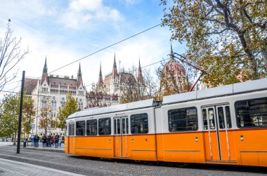 Budapeşte, Macaristan - 6 Kasım 2019: Macaristan Parlamentosu binasının önünde halka açık sarı tramvay gezisi. Macar başkenti toplu taşımacılığı. Şehir ulaşımı. Turist eğlencesi