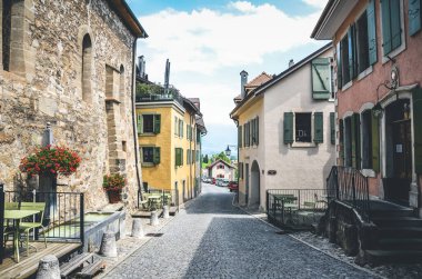 Saint Saphorin, İsviçre - 9 Temmuz 2019: İsviçre Lavaux şarap bölgesindeki St. Saphorin adlı şarap imalathanesinin tarihi caddesi. Geleneksel evler, kaldırımlı sokaklar. Açık hava restoranları