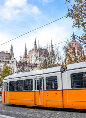 Budapeşte, Macaristan - 6 Kasım 2019: Macaristan Parlamentosu binasının önünde halka açık sarı tramvay gezisi. Macar başkenti toplu taşımacılığı. Şehir ulaşımı. Doğu Avrupa hedefleri