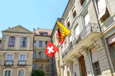 Cenevre, İsviçre - 19 Temmuz 2019: Şehir merkezinde İsviçre bayrağı ve Cenevre bayrağı sallanan tarihi binalar. Şehir merkezindeki tarihi evlerin cepheleri.