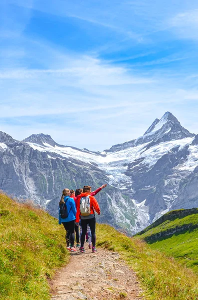 Гриндельвальд, Швейцария - 16 августа 2019 года: Летний альпийский пейзаж. Молодые путешественницы и швейцарские Альпы на заднем плане. Фотография сделана на тропе от Гриндельвальда до Башальпзе — стоковое фото