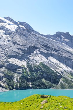 İsviçre, Kandersteg yakınlarındaki Oeschinensee Gölü 'nün dikey fotoğrafı. Turkuaz göl, sarp karlı dağlarla çevrili. İsviçre Alplerinde turistik bir yer. Yaz Alp manzarası