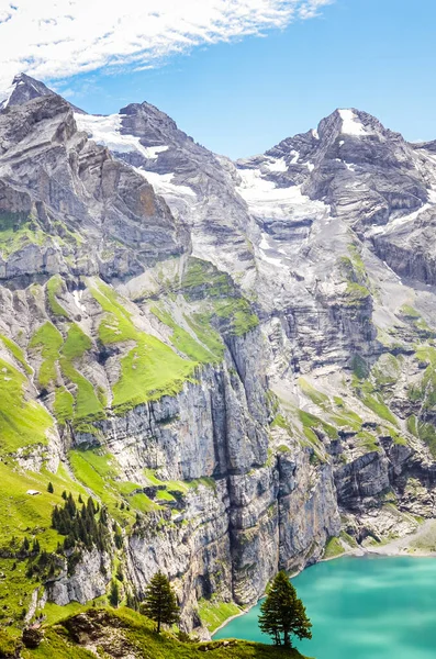 Foto vertical del hermoso lago Oeschinensee de Kandersteg, Suiza. Lago de color turquesa rodeado de escarpadas montañas y rocas. Alpes suizos. Suiza en la temporada de verano. Atracción turística — Foto de Stock