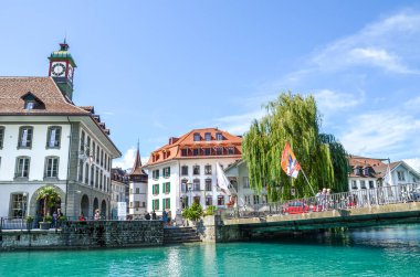Thun, İsviçre - 8 Ağustos 2019: Tarihi Thun kentinin güzel manzarası. Turkuaz Aare nehri kıyısındaki ortaçağ evleri. Kanalda yürüyen insanlar. Güneşli yaz günü