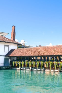 İsviçre 'nin tarihi Thun kentindeki turkuaz Aare Nehri üzerindeki eski ahşap köprü. Köprü inşaatı geleneksel Alp çiçekleriyle süslenmiştir. Turistik bir yer. Dikey fotoğrafçılık