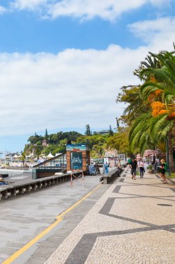 Funchal, Madeira, Portekiz - Sep 10, 2019: Madeiran başkentindeki liman boyunca şehir gezisi. Kaldırımlar, yeşil bitkiler, palmiye ağaçları ve sokaklarda insanlar. Dikey resim