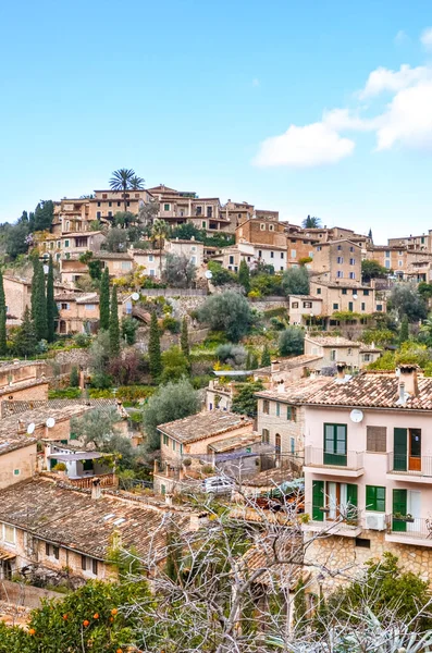 Amazing cityscape of the small coastal village Deia in Mallorca, Spain. Typical houses located in terraces on the hill surrounded by green trees. Spanish tourist attraction. Vertical photo — Stock Photo, Image