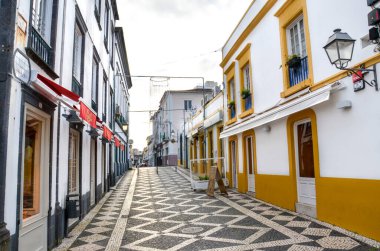 Ponta Delgada, Azores, Portekiz - 12 Ocak 2020: Portekiz 'in tarihi merkezinde bar ve restoranları olan boş cadde. Renkli yüzler, geleneksel evler, kaldırımlı caddeler. Bulutlu