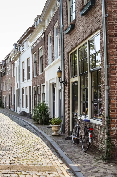 Hertogenbosch, Észak-Brabant, Hollandia - 2018. június 9.: Utca a holland város történelmi központjában. Hagyományos holland épületek, bicikli a ház mellett. Függőleges fénykép — Stock Fotó