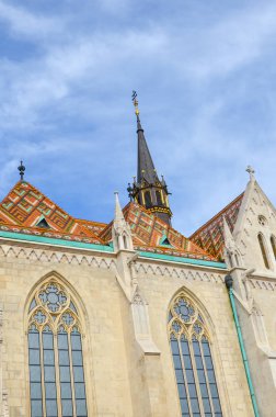 Macaristan, Budapeşte 'deki ünlü Matthias Kilisesi' nin renkli kiremit çatısı. Roma Katolik kilisesi Gotik tarzda inşa edildi. Mavi gökyüzü ve beyaz bulutlar. Yatay fotoğraf. Dikey fotoğraf.