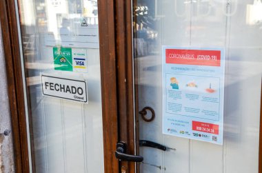 Faro, Portekiz - 16 Mart 2020: Portekizce ve İngilizce Coronavirus Güvenlik Talimatları broşürü ile restoranın kapalı ön kapısı. Restoranlar COVID-19 salgını yüzünden kapalı..