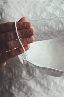 Beyaz tıbbi maske tutan gelin elleri. Coronavirus salgını sırasında gelinlik giymiş bir kadın. COVID-19 salgınının neden olduğu düğünler iptal edildi ya da ertelendi. Coronavirus konsepti, kavramsal fotoğraf.