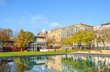 Budapeşte, Macaristan - 6 Kasım 2019: Sonbahar renklerinde ağaçları olan Macar başkent sokakları. Ön plandaki çeşmeden gelen su. Yatay fotoğraf.