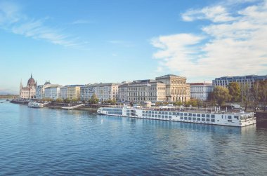 Budapeşte, Macaristan - 6 Kasım 2019: Macar başkentinde Tuna Nehri 'nin suları ve büyük bir turist yolcu gemisi. Arka planda tarihi bir merkez var. Bulutlar ve mavi gökyüzü. Yatay fotoğraf.