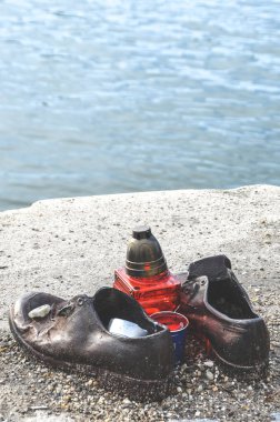 Budapeşte, Macaristan - 6 Kasım 2019: Danube Bank 'ın Ayakkabıları. 2. Dünya Savaşı sırasında faşistler tarafından öldürülen Yahudilerin anıtı. Demir ayakkabılar, kırmızı mum. Arka planda Tuna Nehri bulanık.