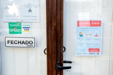 Faro, Portekiz - 16 Mart 2020: Portekizce ve İngilizce Coronavirus Güvenlik Talimatları broşürü ile restoranın kapalı ön kapısı. Restoranlar COVID-19 salgını yüzünden kapalı..