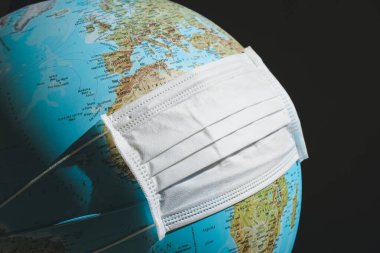 Beyaz tıbbi maskeli dünya küresi. Coronavirus, COVID-19 konsepti. 2019-Ncov virüsü yüzünden dünya çapında tecrit ve karantina durumu. Dünya gezegeni salgın halinde. Seyahat kısıtlamaları.