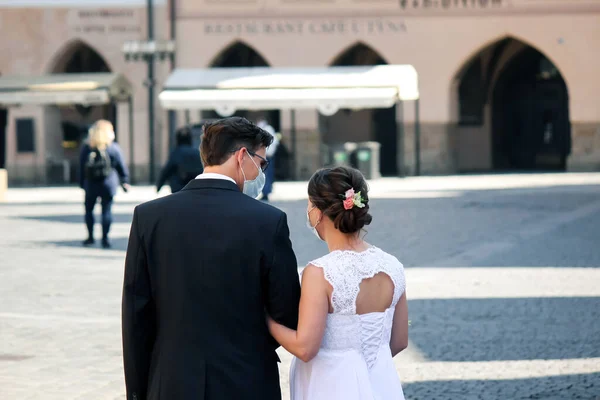 Prag, Çek Cumhuriyeti - 23 Nisan 2020: Eski kentte maskeli bir düğün çifti. Koronavirüs salgını sırasında düğün. COVID-19 düğünleri. Yatay fotoğraf.
