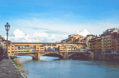 Ünlü Ponte Vecchio Köprüsü, Floransa, Toskana, İtalya 'daki Arno Nehri üzerindeki ortaçağ taş köprüsü. İtalyan şehrinin büyük simgesi. Mavi gökyüzü, arka planda bulutlar. İnanılmaz bir şehir manzarası.