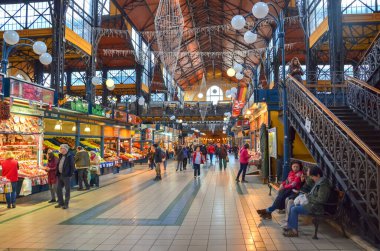 Budapeşte, Macaristan - 6 Kasım 2019: İnsanlar Büyük Pazar Salonundan alışveriş yapıyor. Şehirdeki en büyük kapalı market. İnsanlar alışveriş yapıyor. Çatı altında pazar. Merdivenler ikinci kata çıkıyor. Yatay fotoğraf.