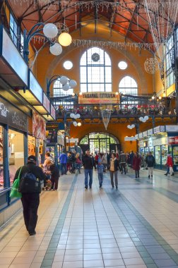 Budapeşte, Macaristan - 6 Kasım 2019: İnsanlar Büyük Pazar Salonundan alışveriş yapıyor. Şehirdeki en büyük kapalı market. İnsanlar alışveriş yapıyor. Çatı altında pazar. Merdivenler ikinci kata çıkıyor. Dikey fotoğraf.