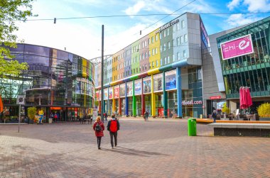 Amsterdam, Hollanda - 27 Nisan 2019: Hollanda başkentinin iş bölgesi. Renkli yüzlü ticari binalar ve oteller. Sokaktaki insanlar, günlük hayat..