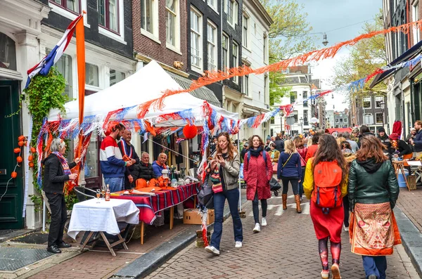 Amsterdam, Hollanda - 27 Nisan 2019: Geleneksel bit pazarında Kings günü, Koningsdag 'da insanlar alıp satıyor. Hollanda bayrakları ve ulusal renklerle süslenmiş sokaklar.