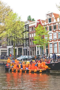 Amsterdam, Hollanda - 27 Nisan 2019: Hollanda Kralı Willem-Alexander 'ın doğum günü olan Koningsdag, Krallar Günü' nü kutlarken ulusal turuncu renkte giyinmiş insanlarla kanal üzerinde parti tekneleri.