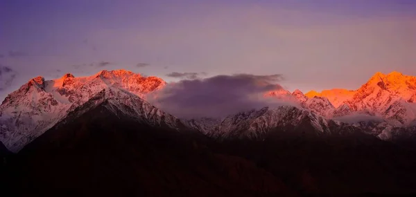 Прекрасный облачный восход солнца в горах со снежным хребтом — стоковое фото