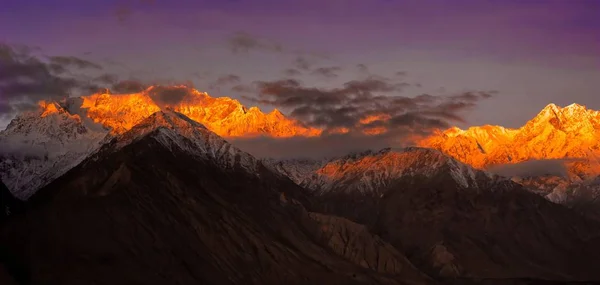 Прекрасный облачный восход солнца в горах со снежным хребтом — стоковое фото